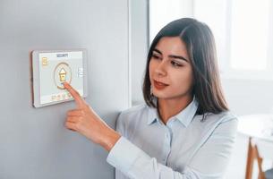 mulher está dentro de casa controlando tecnologia de casa inteligente foto