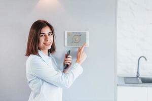 mulher está dentro de casa controlando tecnologia de casa inteligente foto