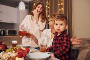 passar o fim de semana juntos. família feliz de mãe, filha e filho está na cozinha à noite foto