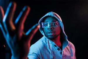 em óculos especiais. iluminação neon futurista. jovem afro-americano no estúdio foto