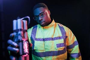 policial com bomba. iluminação neon futurista. jovem afro-americano no estúdio foto