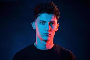 fechar retrato. iluminação neon. jovem europeu está no estúdio escuro foto