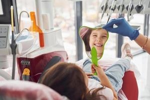 olha para o espelho. menina visitando dentista na clínica. concepção de estomatologia foto