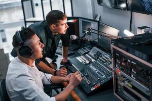 concepção de trabalho em equipe. dois caras estão dentro de casa no estúdio de rádio estão ocupados com a transmissão foto