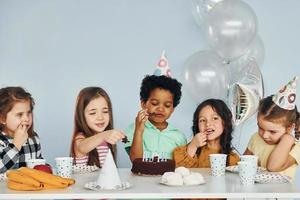 bolo de férias. as crianças comemorando a festa de aniversário dentro de casa se divertem juntas foto