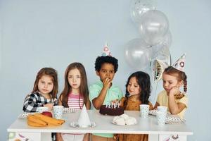 bolo de férias. as crianças comemorando a festa de aniversário dentro de casa se divertem juntas foto