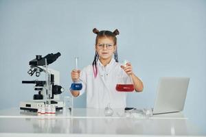 menina de casaco jogando um cientista no laboratório usando equipamentos foto