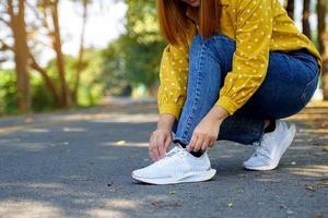 mulher asiática curvar-se para amarrar cadarços enquanto caminhava nas ruas do park.soft e foco seletivo. foto