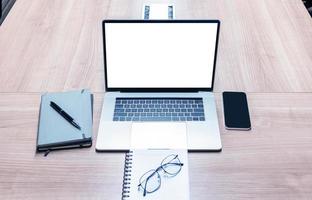 tela branca de exibição superior no laptop com notebook e óculos na mesa na sala de reuniões foto