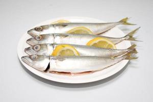 peixe fresco com limão em um prato branco foto