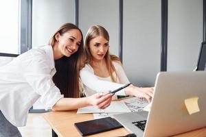 duas mulheres adultas em roupas formais estão juntas no escritório foto