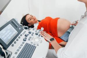 diagnóstico por ultrassom. mulher grávida está na clínica no gabinete e faz exame de saúde foto