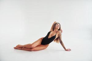 deitado no chão. bela mulher desportiva sedutora com corpo sexy está posando no estúdio foto