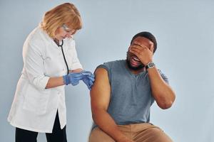 médico sênior dando injeção para jovem afro-americano no hospital foto