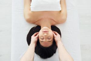 jovem está deitada quando homem fazendo massagem de seu corpo no spa foto