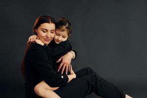 mãe e filha estão juntas no estúdio contra fundo preto foto