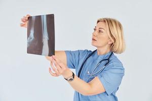 mantém o raio-x. médica profissional de meia-idade de uniforme e com estetoscópio foto