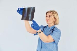 mantém o raio-x. médica profissional de meia-idade de uniforme e com estetoscópio foto