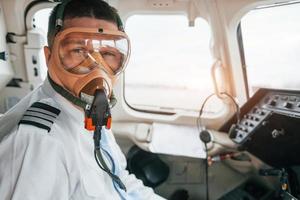 em máscara de oxigênio. piloto no trabalho no avião de passageiros. preparando para decolagem foto