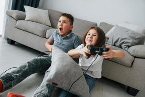 jogando video games. crianças se divertindo na sala de casa durante o dia juntos foto