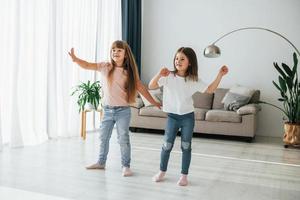 dançando juntos. crianças se divertindo na sala doméstica durante o dia foto