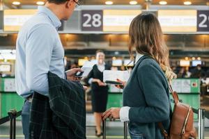 olhando para o empregado. jovem casal está no aeroporto juntos foto