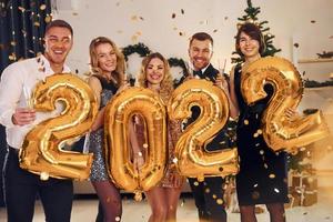 2022 ano. grupo de pessoas tem uma festa de ano novo dentro de casa juntos foto