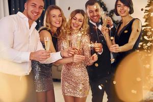 celebração do ano novo. grupo de pessoas tem uma festa de ano novo dentro de casa juntos foto