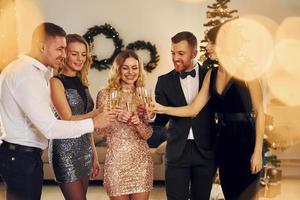 tempo de natal. grupo de pessoas tem uma festa de ano novo dentro de casa juntos foto