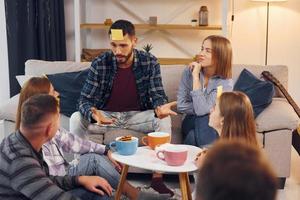 jogando quem sou eu jogo. grupo de amigos tem festa dentro de casa juntos foto