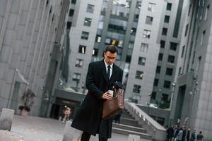 em roupas formais. empresário de terno preto e gravata está ao ar livre na cidade foto