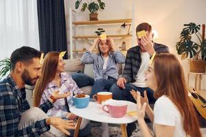 adesivos amarelos na testa. grupo de amigos tem festa dentro de casa juntos foto