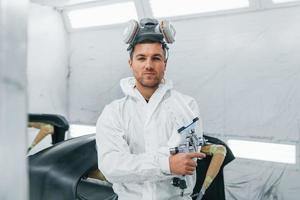 pronto para a pintura. homem de uniforme está trabalhando no auto serviço foto