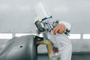 pronto para a pintura. homem de uniforme está trabalhando no auto serviço foto