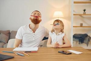 sentado à mesa e se divertindo. pai com sua filha está em casa juntos foto