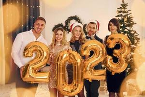 2023 está chegando. grupo de pessoas tem uma festa de ano novo dentro de casa juntos foto