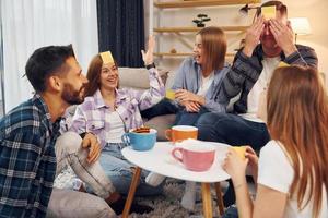 adesivos amarelos na testa. grupo de amigos tem festa dentro de casa juntos foto