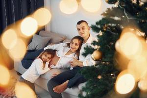 com árvore de Natal. família feliz comemorando feriados dentro de casa juntos foto