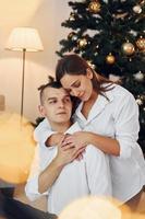 abraçando um ao outro. lindo casal comemorando feriados juntos dentro de casa foto