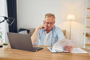 trabalhando usando laptop. homem sênior com roupas bonitas está em casa foto