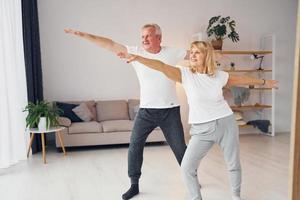 exercícios esportivos. homem e mulher sênior estão juntos em casa foto