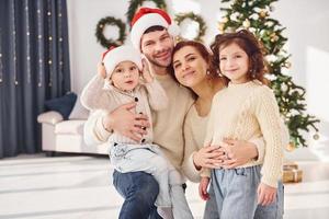 em chapéus de natal. família comemorando o ano novo com seus filhos em casa foto