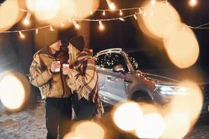 com bebidas quentes. casal dançando na floresta e comemorando o ano novo foto