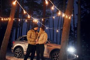 carro está em segundo plano. casal dançando na floresta e comemorando o ano novo foto