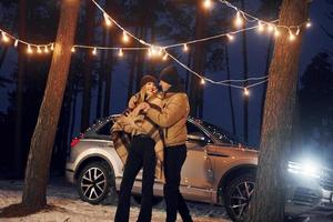 carro está em segundo plano. casal dançando na floresta e comemorando o ano novo foto