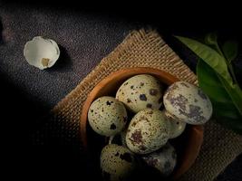 ovos de codorna de codorna, uma coleção de ovos de codorna em uma placa de madeira com fundo de areia preta foto