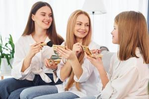 ensinando a fazer maquiagem. jovem mãe com suas duas filhas em casa durante o dia foto