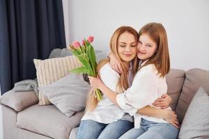 flores no feriado. jovem mãe com sua filha está em casa durante o dia foto