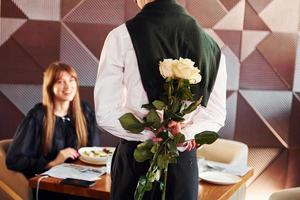 garçom dá flores para uma mulher. dentro do novo restaurante de luxo moderno foto