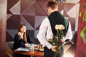 garçom dá flores para uma mulher. dentro do novo restaurante de luxo moderno foto